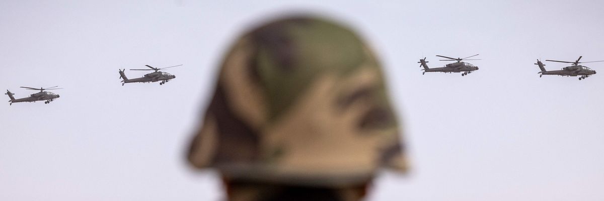 Soldier looks on as US army AH-64 Apache attack helicopters fly over