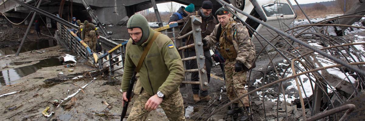 Soldiers cross a destroyed bridge.