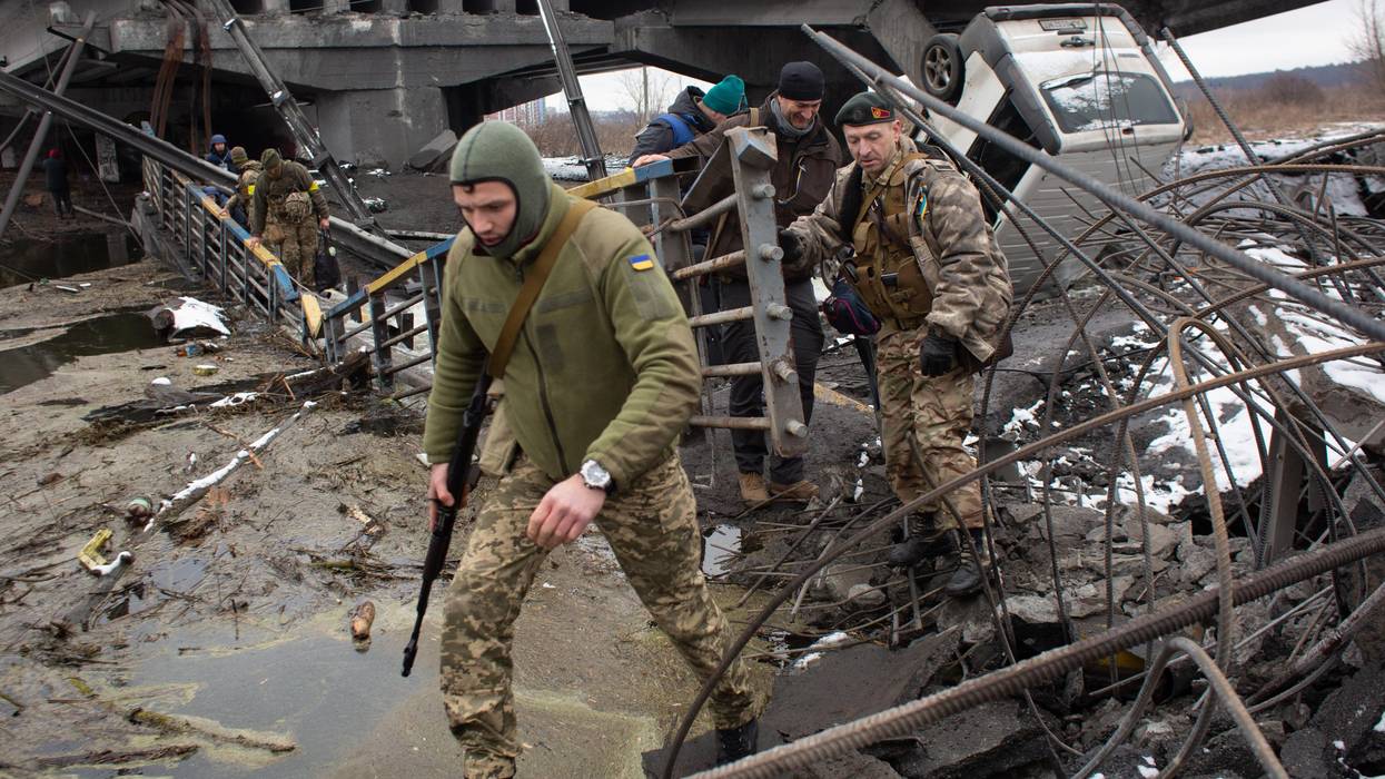 Soldiers cross a destroyed bridge.