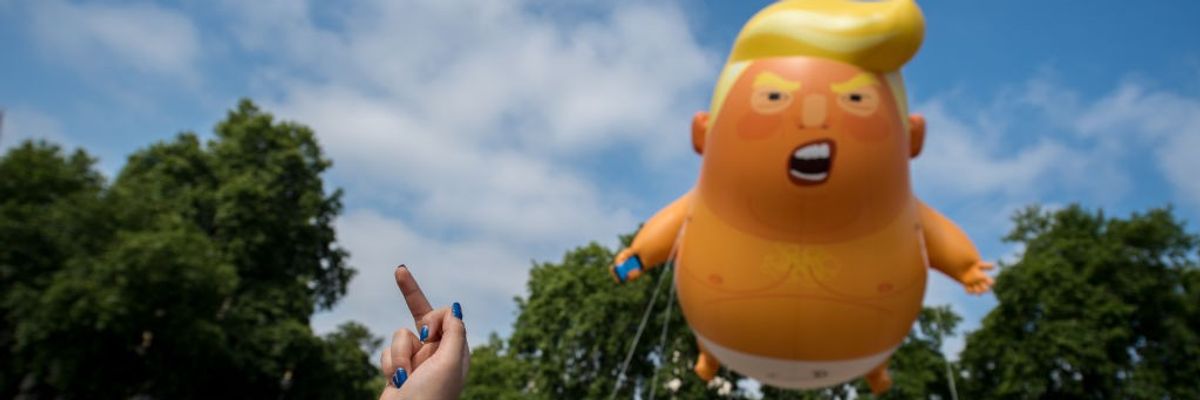 Someoen flips off the Trump Baby balloon.