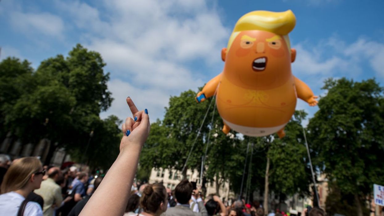 Someoen flips off the Trump Baby balloon.