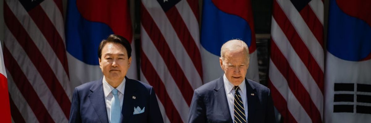South Korean President Yoon Suk Yeol and President Joe Biden stand in front of flags.