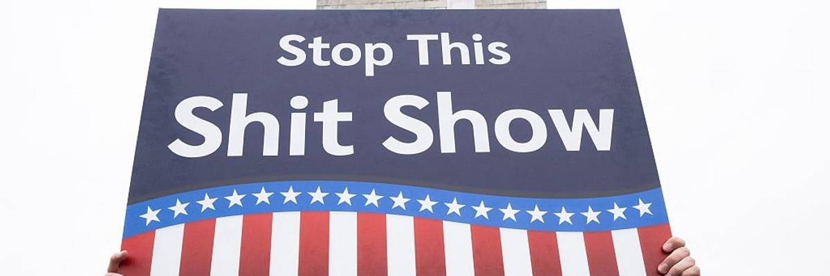 "Stop this shit show," sign says.