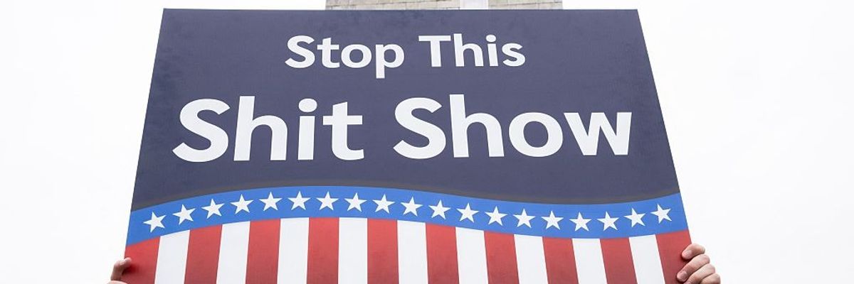 "Stop this shit show," sign says.