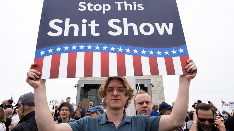 "Stop this shit show," sign says.