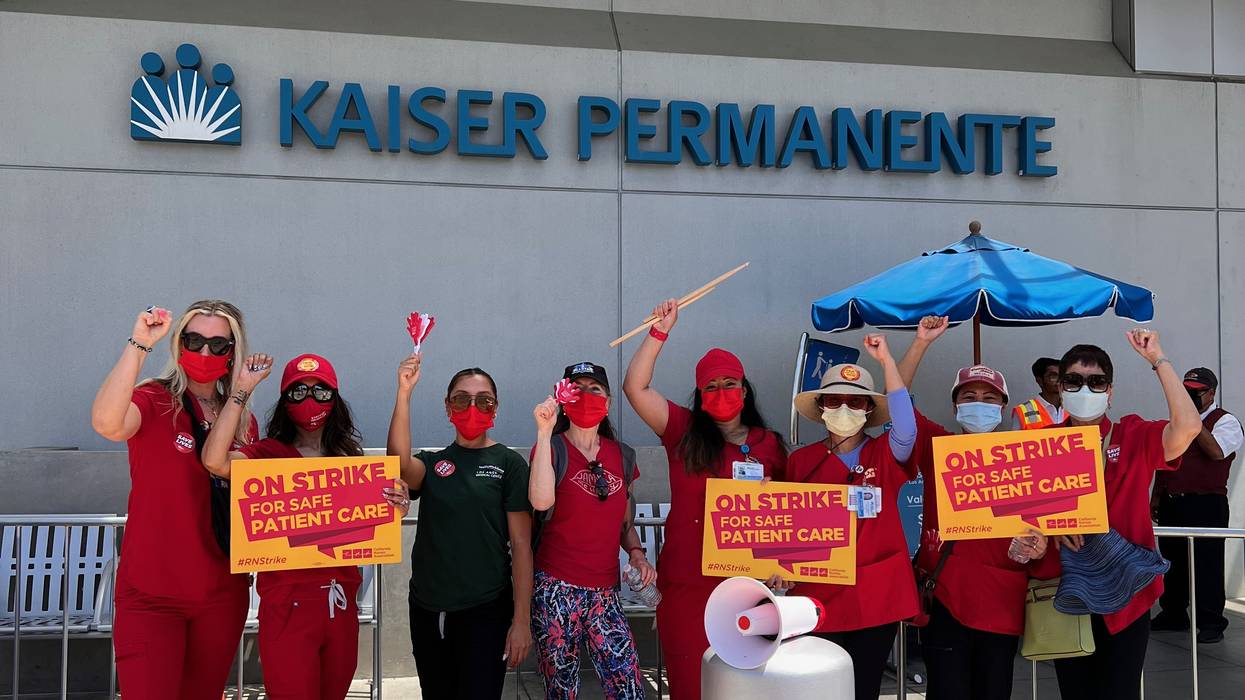 Striking nurses stand in front of a Kaiser Permanente building.