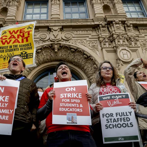Striking San Francisco teachers hold signs reading, "On Strike for Fully Funded Family Healthcare" and other messages