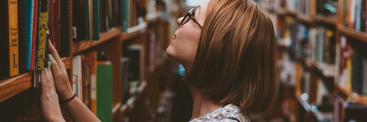 Student standing among library bookshelves.