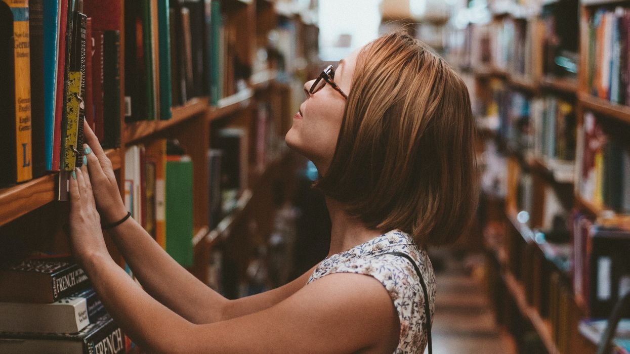 Student standing among library bookshelves.