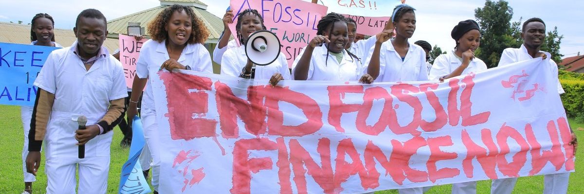Students carry a white banner against a green lawn.