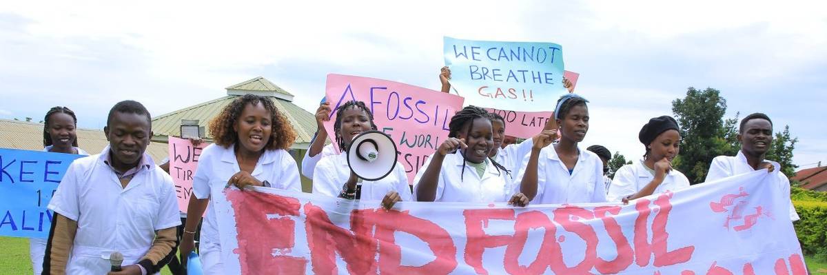 Students carry a white banner against a green lawn.