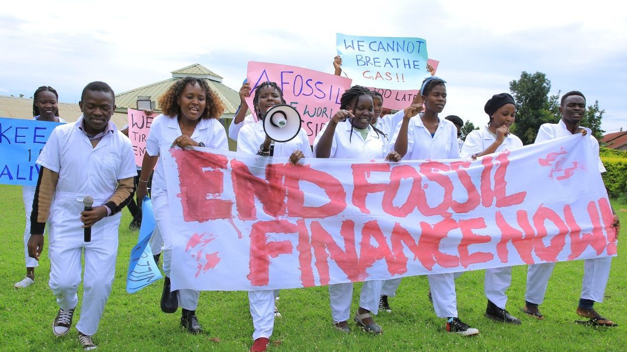 Students carry a white banner against a green lawn.