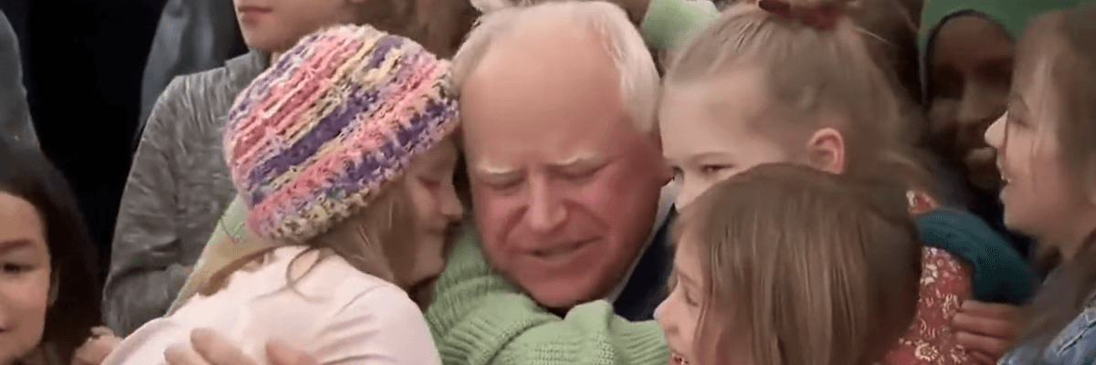 Students hug Tim Walz after he signs free school meal bill.