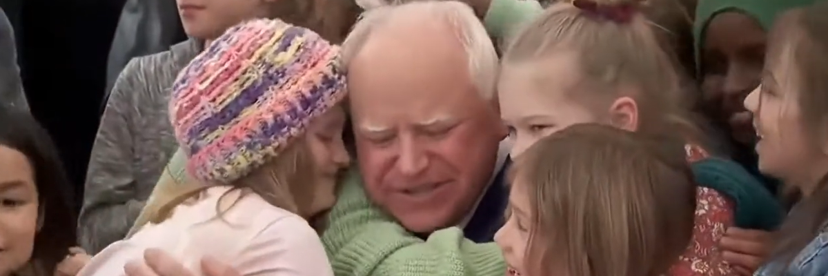 Students hug Tim Walz after he signs free school meal bill.