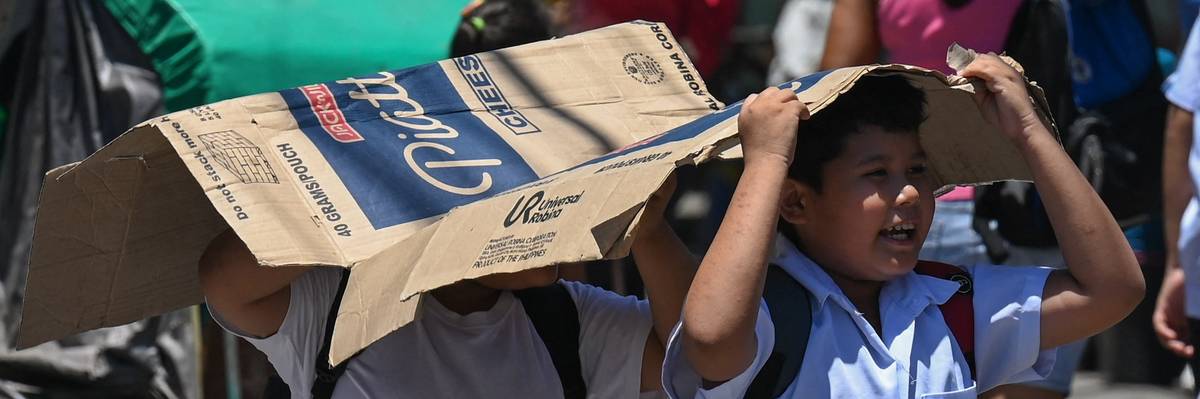 Students use a piece of cardboard to protect themselves from the sun