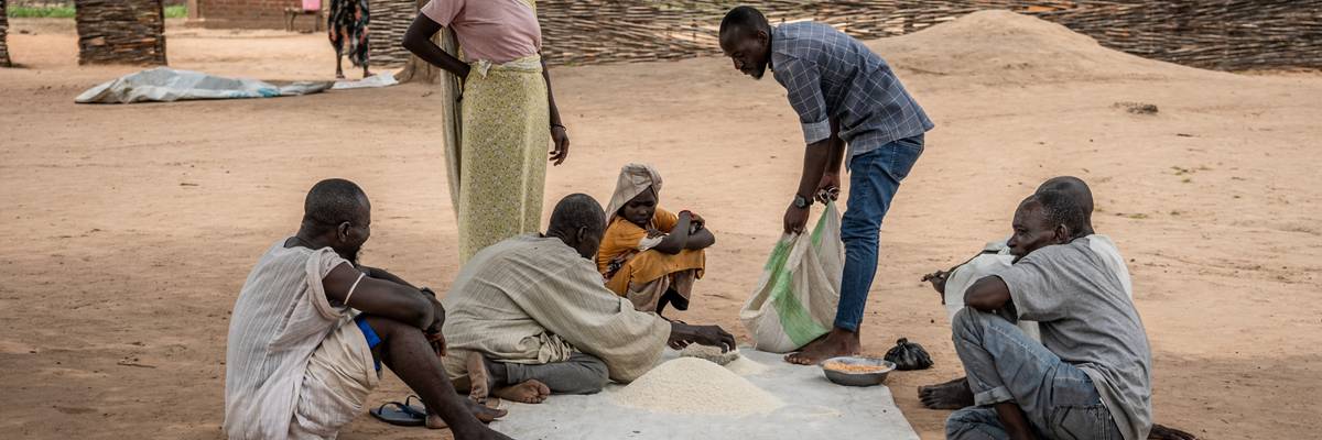 Sudanese refugees in the Korsi camp sit together around a pile of ground cassava on August 10, 2024.
