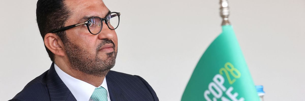 Sultan Ahmed Al Jaber sits next to a flag saying COP28 UAE.