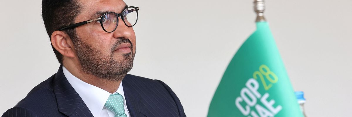 Sultan Ahmed Al Jaber sits next to a flag saying COP28 UAE.