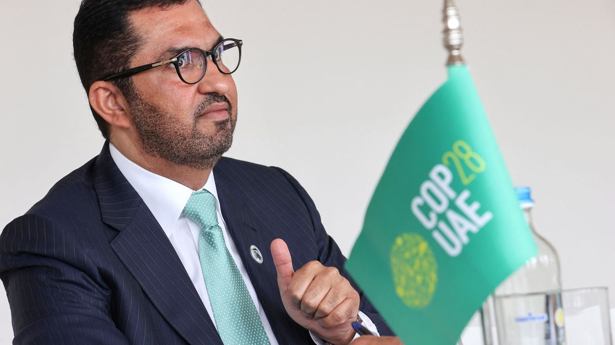 Sultan Ahmed Al Jaber sits next to a flag saying COP28 UAE.