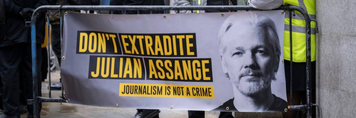 Supporters carry signs calling for release of Julian Assange.
