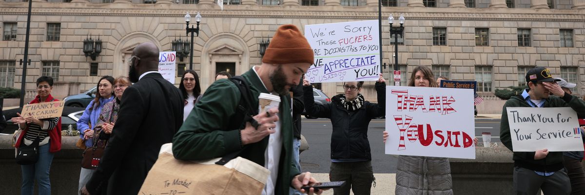 Supporters hold signs thanking USAID employees