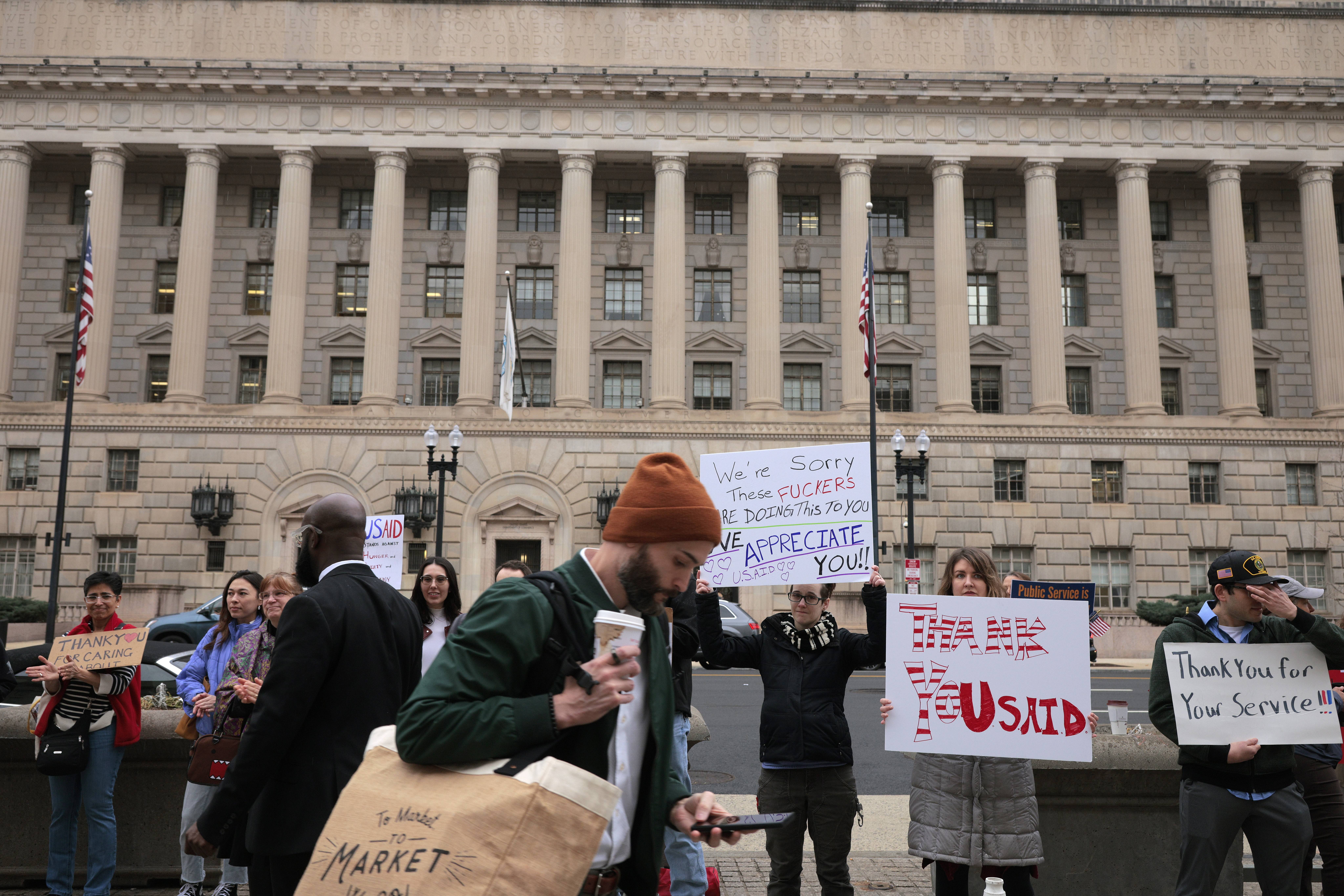 Supporters hold signs thanking USAID employees