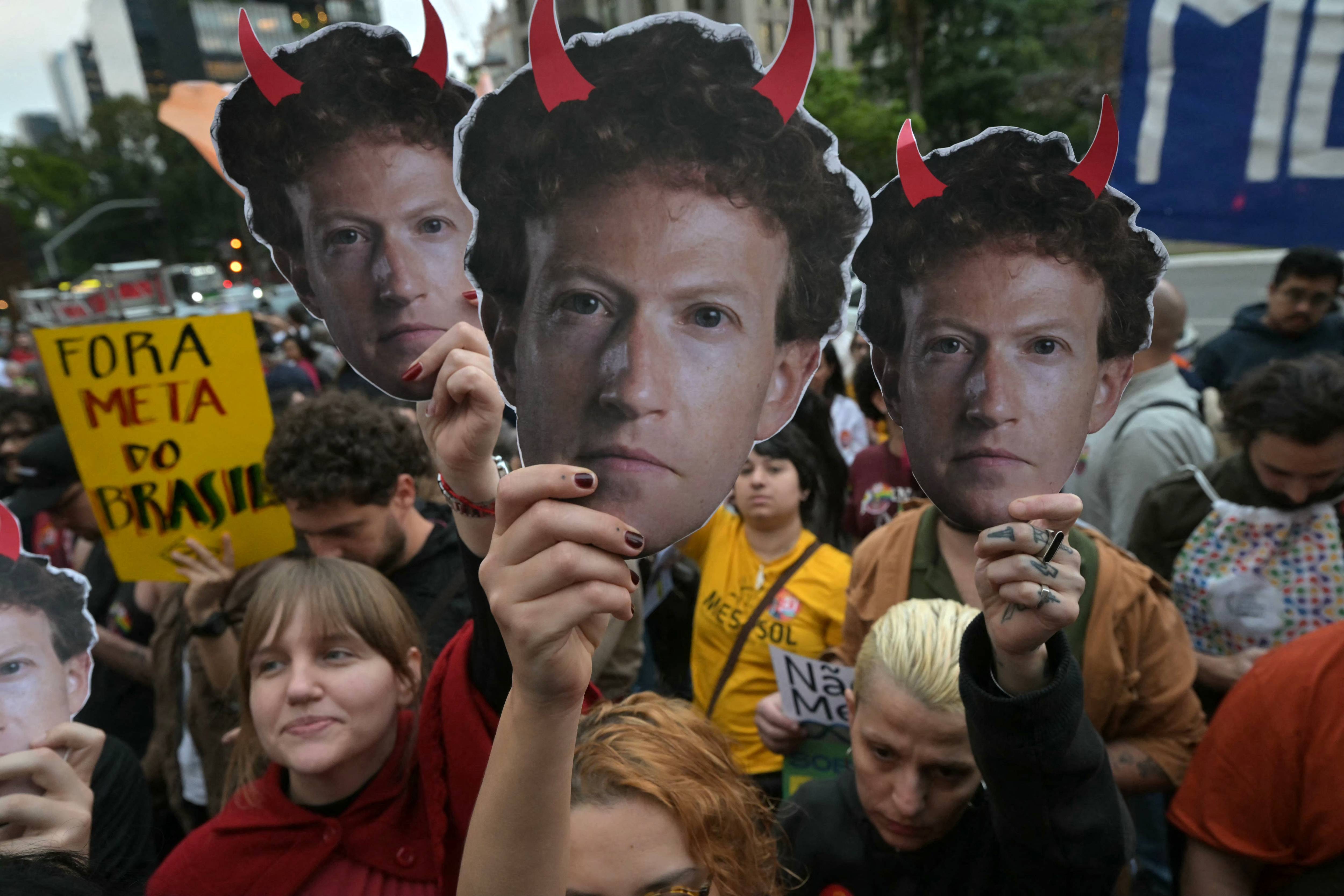 Supporters of Brazilian President Luiz Inácio Lula da Silva hold masks depicting Meta CEO Mark Zuckerberg with red horns