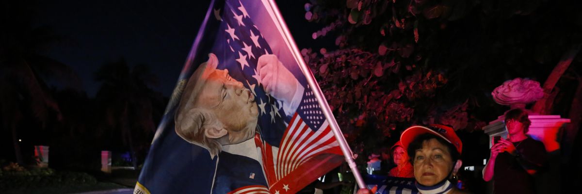 Supporters of former President Donald Trump hold flags in front of his home at Mar-a-Lago on August 8, 2022 in Palm Beach, Florida.