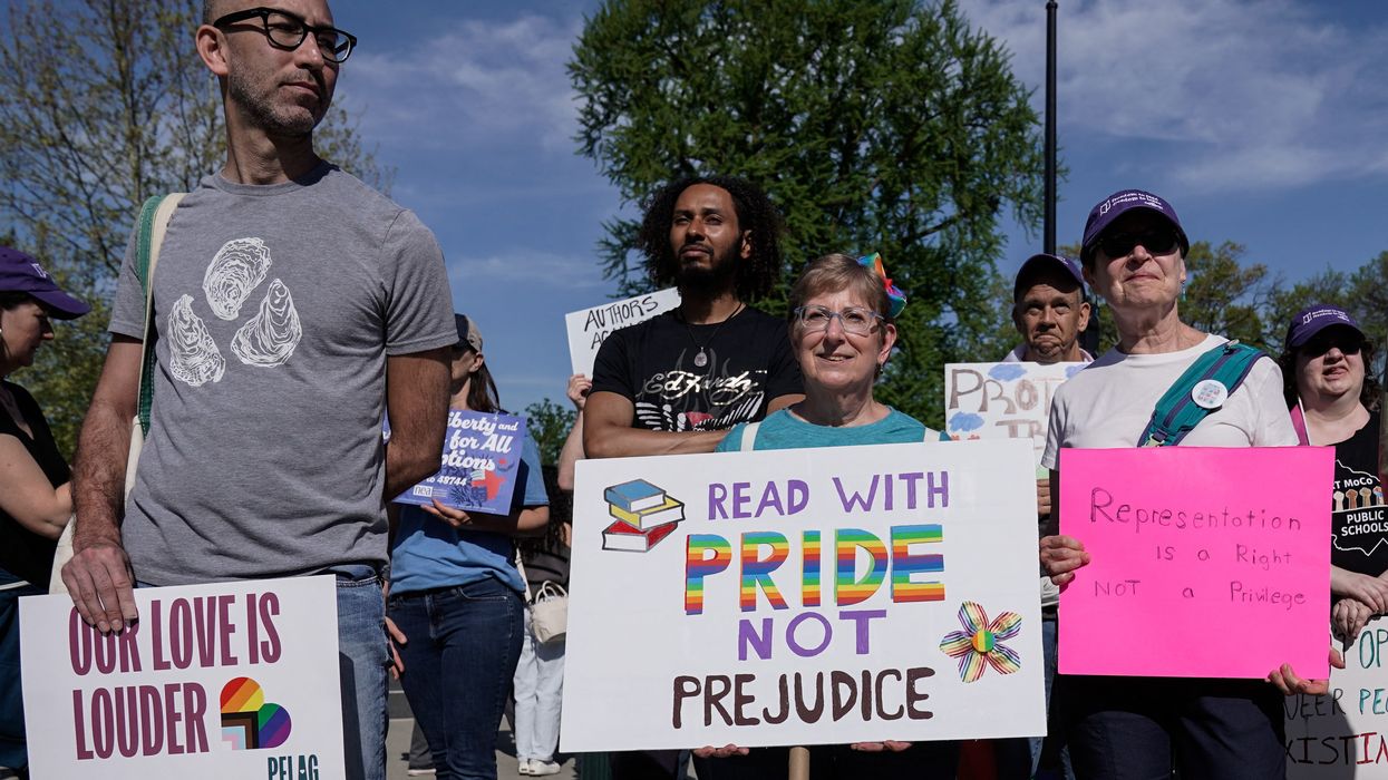 Supporters of LGBTQ+ rights hold signs as they demonstrate outside the U.S. Supreme Court