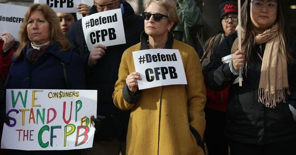Supporters of the Consumer Financial Protection Bureau hold signs as they gather in front of the agency November 27, 2017 in Washington, D.C. President Trump has picked White House Budget Director Mick Mulvaney as the acting director after former director Richard Cordray stepped down and named his chief of staff Leandra English as acting director, setting up a possible court battle over who will lead the agency. (Photo: Alex Wong/Getty Images)