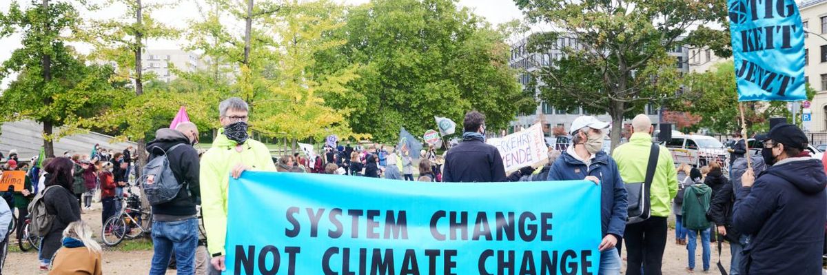"System change not climate change" is written on a banner at a rally