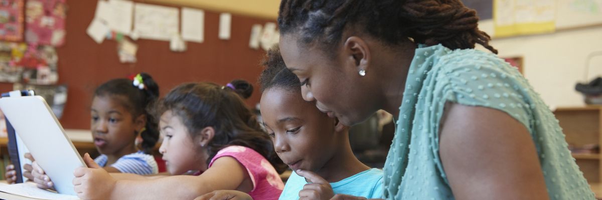 Teacher helping student with digital tablet
