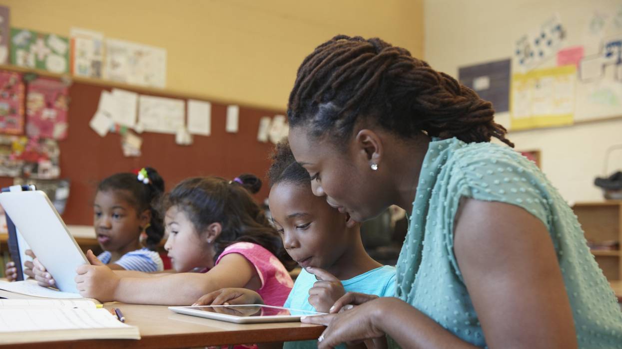 Teacher helping student with digital tablet