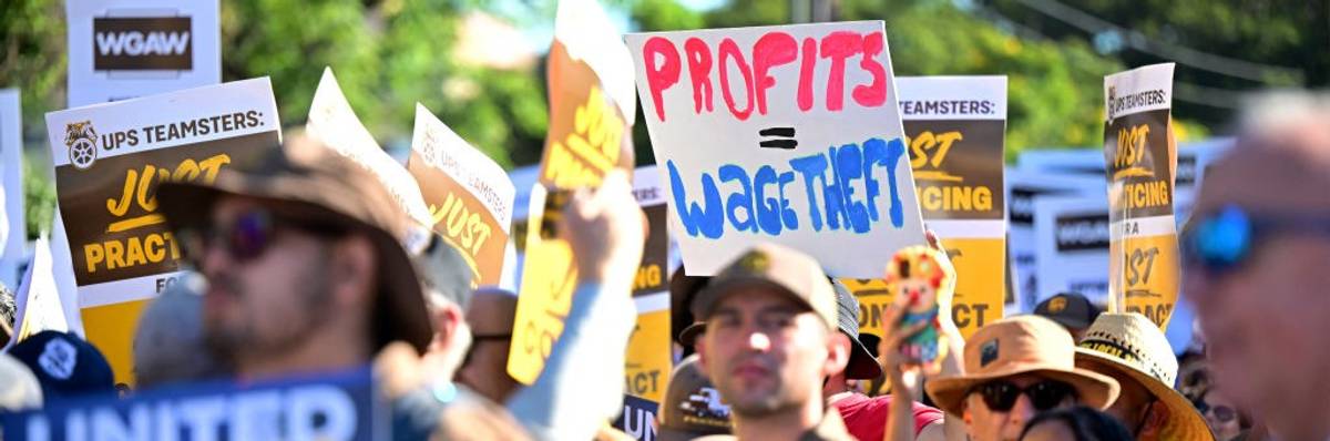 Teamsters and WGA members march with signs, one saying "Profits = Wage Theft."