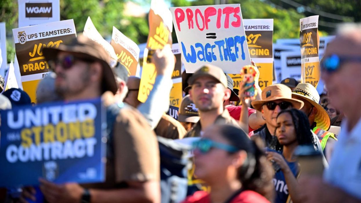 Teamsters and WGA members march with signs, one saying "Profits = Wage Theft."