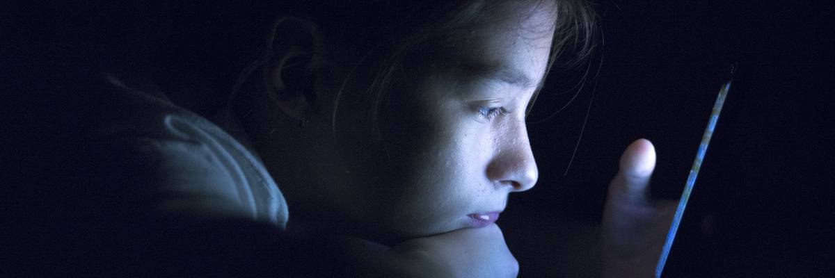 Teenager sending email from smart phone in her bed