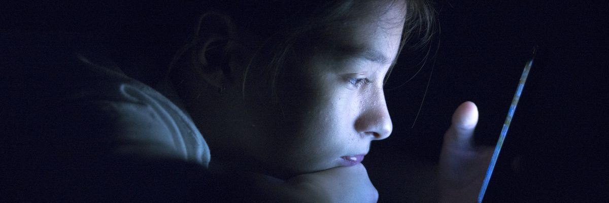 Teenager sending email from smart phone in her bed