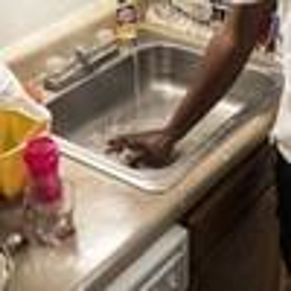 Terrence Carter mixes bleach and soap with water before washing dishes on September 1, 2022 in Jackson, Mississippi.