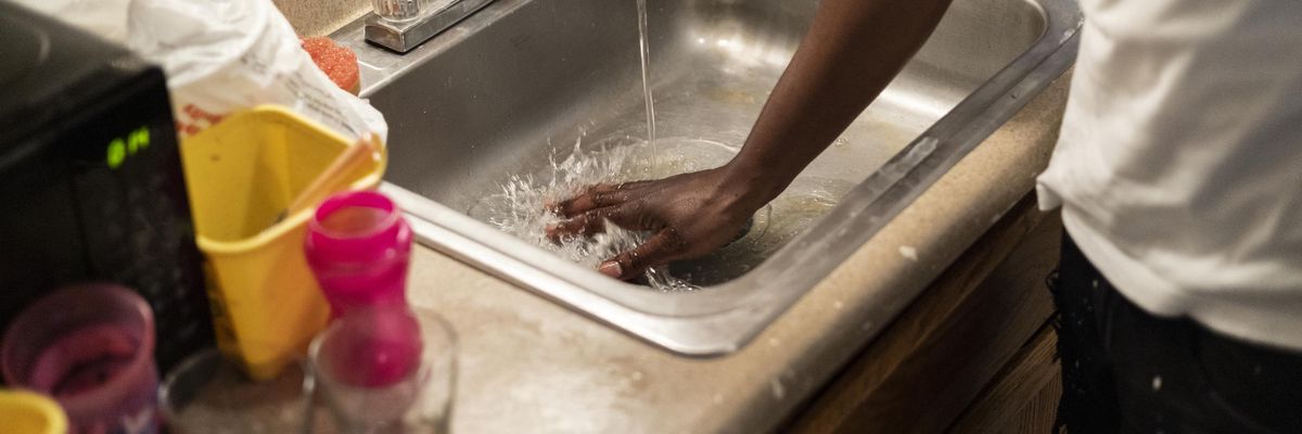 Terrence Carter mixes bleach and soap with water before washing dishes on September 1, 2022 in Jackson, Mississippi.