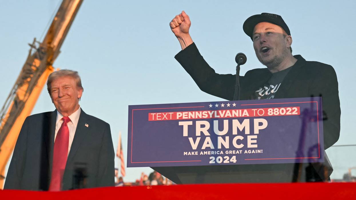 Tesla CEO Elon Musk (R) speaks on stage as he joins Donald Trump