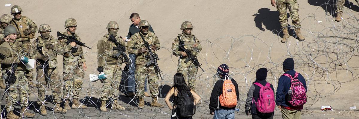 Texas National Guard members stand next to a razor wire fence in El Paso to prevent Latin American migrants waiting in Ciudad Juarez from entering the United States on December 21, 2022