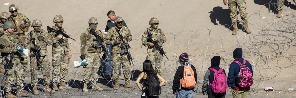 Texas National Guard members stand next to a razor wire fence in El Paso to prevent Latin American migrants waiting in Ciudad Juarez from entering the United States on December 21, 2022