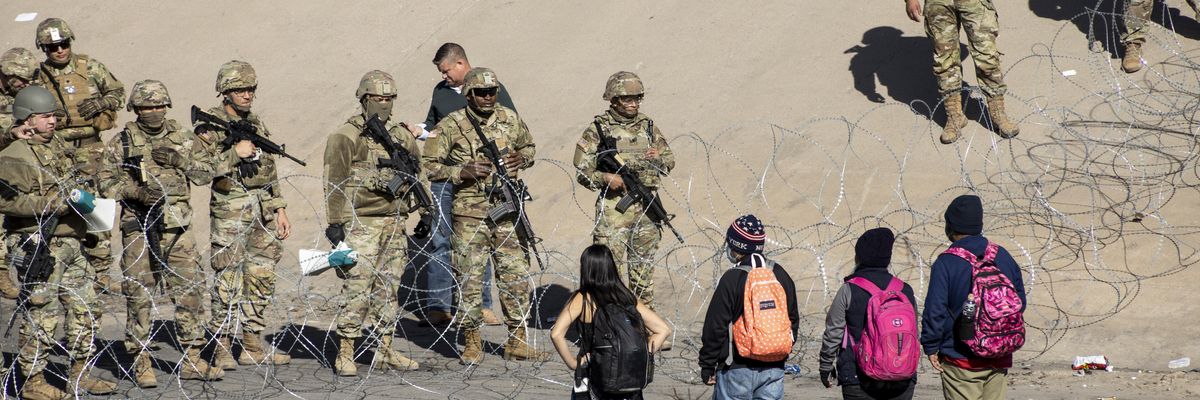 Texas National Guard members stand next to a razor wire fence in El Paso to prevent Latin American migrants waiting in Ciudad Juarez from entering the United States on December 21, 2022