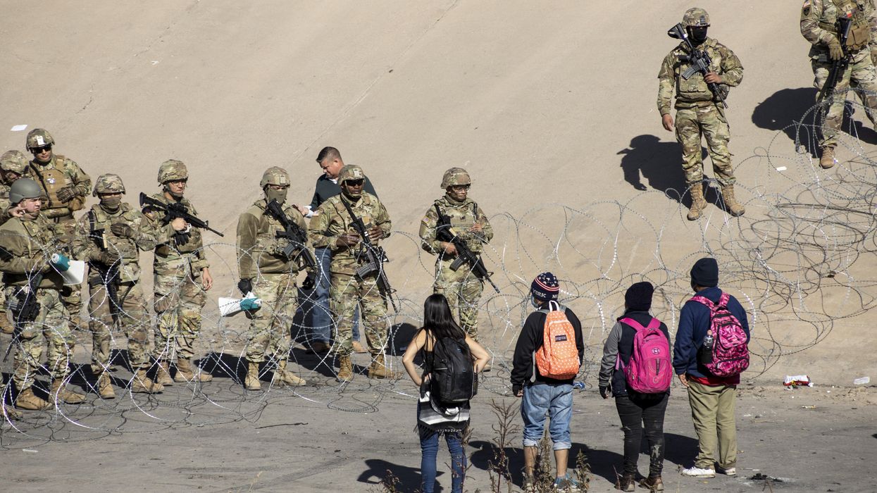 Texas National Guard members stand next to a razor wire fence in El Paso to prevent Latin American migrants waiting in Ciudad Juarez from entering the United States on December 21, 2022
