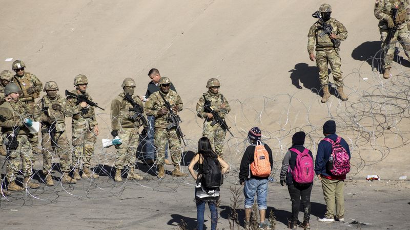 Texas National Guard members stand next to a razor wire fence in El Paso to prevent Latin American migrants waiting in Ciudad Juarez from entering the United States on December 21, 2022