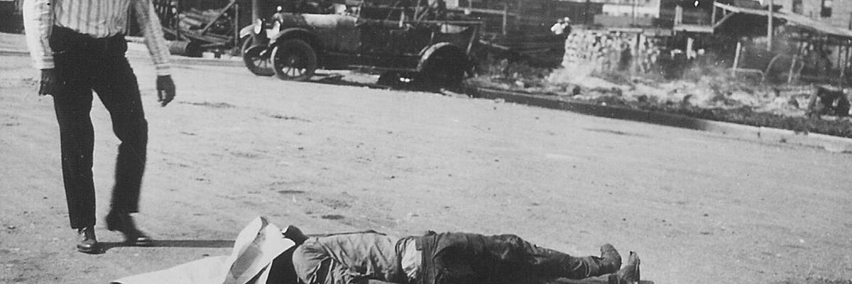 The body of an unidentified black victim of the Tulsa Race Massacre lies in the street as a white man stands over him, Tulsa, Oklahoma, June 1, 1921