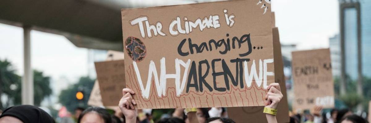 "The Climate Is Changing—Why Arent' We?" signs says