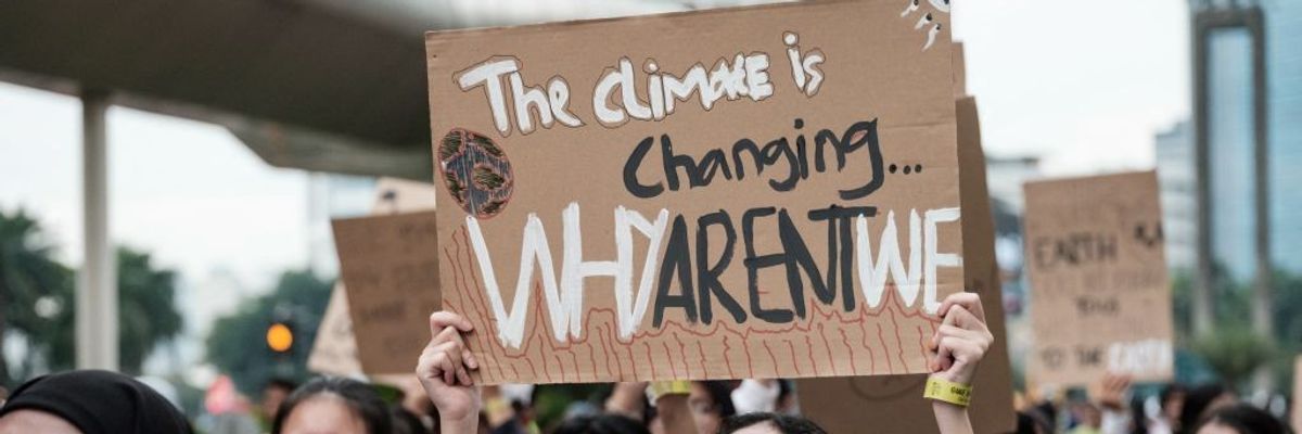 "The Climate Is Changing—Why Arent' We?" signs says