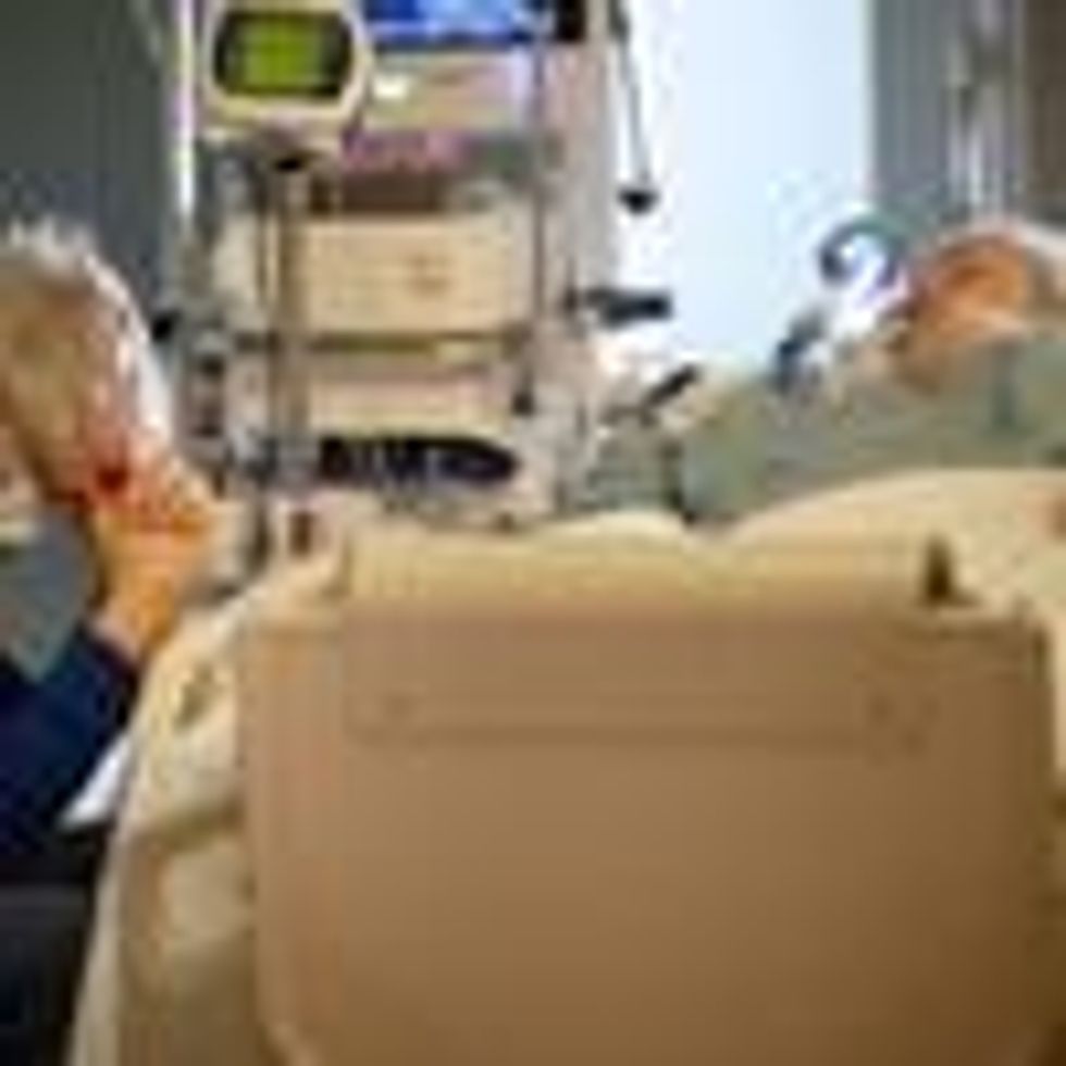 The husband of a Covid-19 patient prays at her bedside