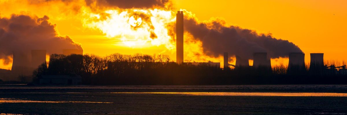 The sun rises behind cooling towers of a power plant in the English village Drax